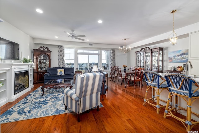 living room featuring ceiling fan with notable chandelier and hardwood / wood-style flooring