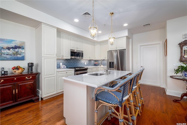 kitchen featuring white cabinetry, sink, stainless steel appliances, dark hardwood / wood-style floors, and pendant lighting