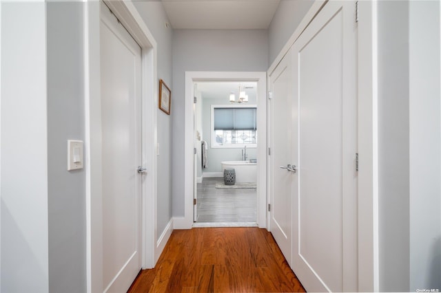 hall with hardwood / wood-style floors and a notable chandelier