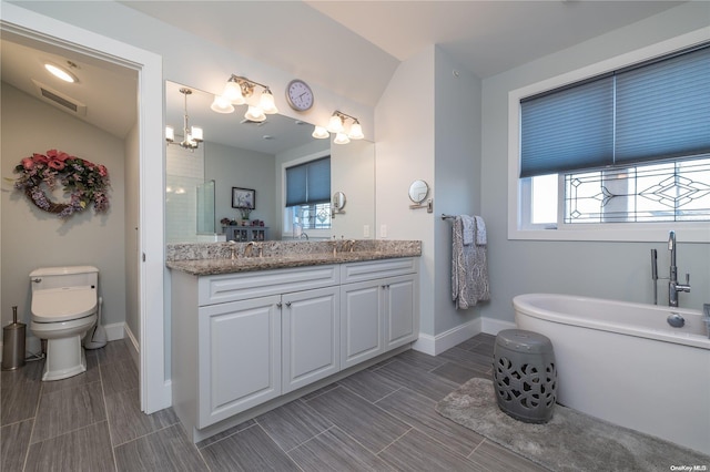 bathroom featuring a washtub, vanity, a chandelier, and toilet