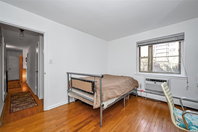 bedroom with an AC wall unit and hardwood / wood-style floors