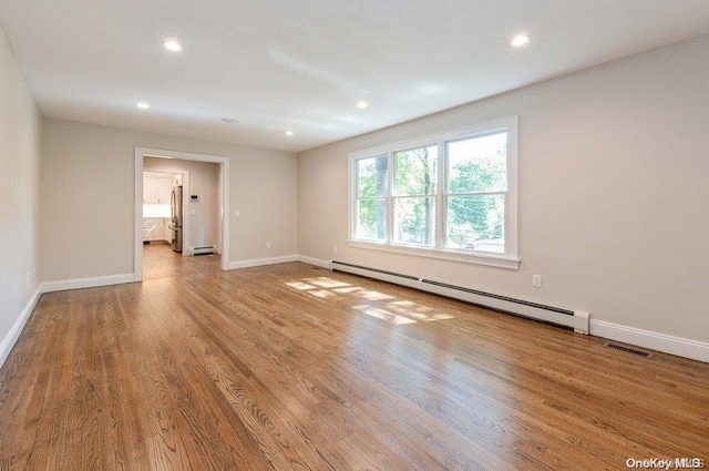 unfurnished room featuring a baseboard radiator and light hardwood / wood-style floors