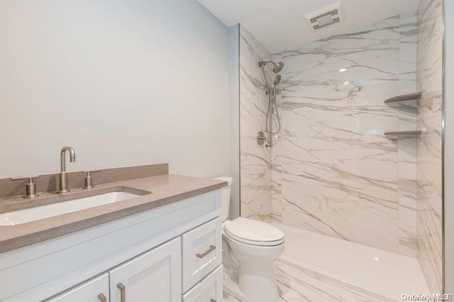 bathroom featuring toilet, vanity, and tiled shower