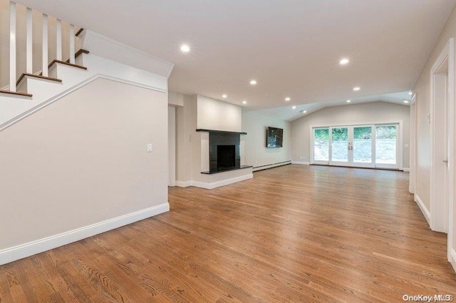 unfurnished living room featuring baseboard heating, vaulted ceiling, and light wood-type flooring