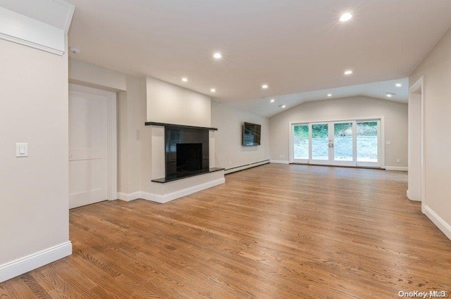 unfurnished living room featuring vaulted ceiling, a baseboard heating unit, and light hardwood / wood-style flooring