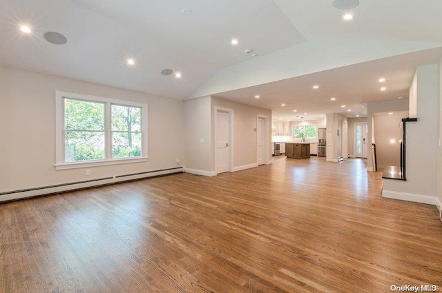 unfurnished living room featuring lofted ceiling, light hardwood / wood-style floors, and a baseboard radiator