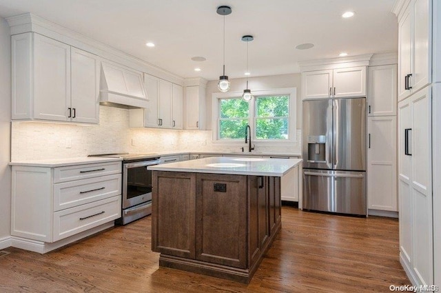 kitchen featuring stainless steel appliances, dark hardwood / wood-style flooring, decorative light fixtures, white cabinets, and custom range hood