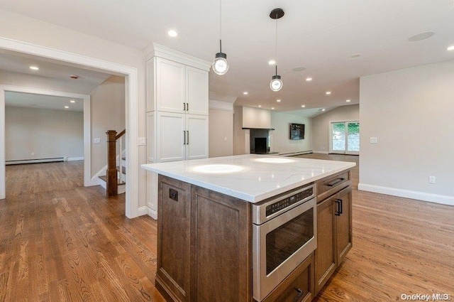 kitchen with pendant lighting, white cabinets, oven, a baseboard radiator, and light hardwood / wood-style floors