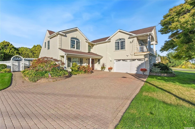 view of property featuring a front yard, a balcony, and a garage