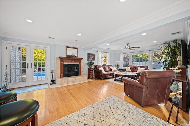 living room featuring french doors, ornamental molding, a wealth of natural light, and light hardwood / wood-style flooring