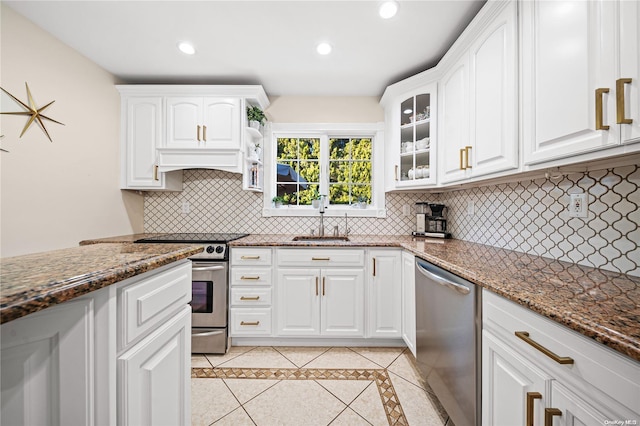 kitchen with appliances with stainless steel finishes, tasteful backsplash, dark stone counters, sink, and white cabinetry