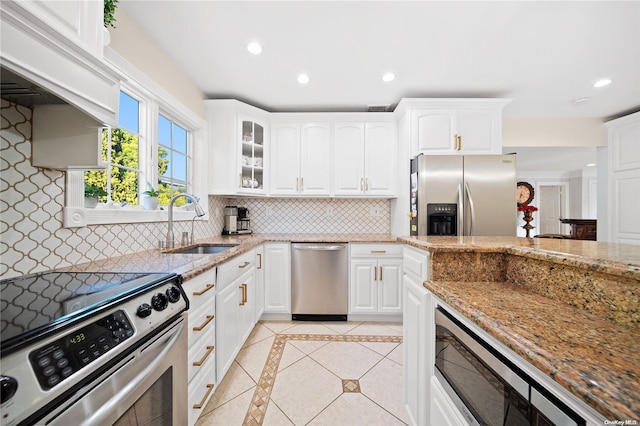 kitchen with light stone countertops, stainless steel appliances, white cabinetry, and sink