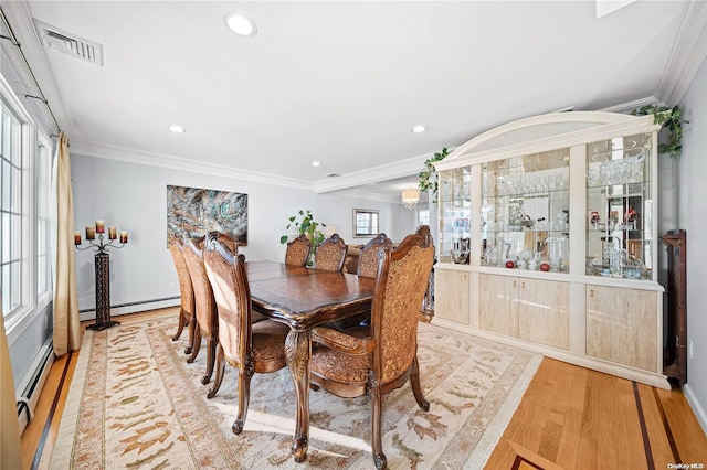 dining room with light wood-type flooring, crown molding, and a baseboard heating unit