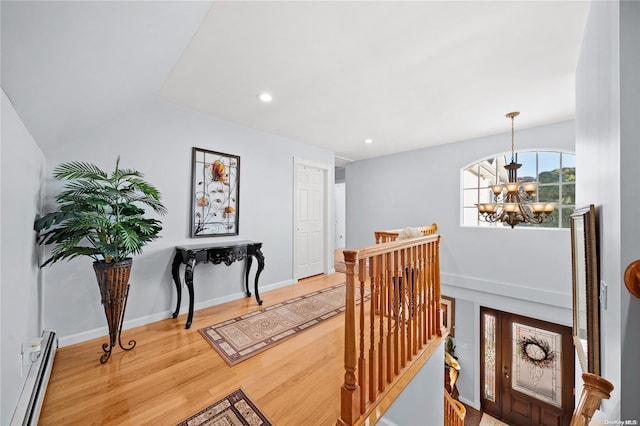 corridor featuring wood-type flooring, vaulted ceiling, an inviting chandelier, and baseboard heating