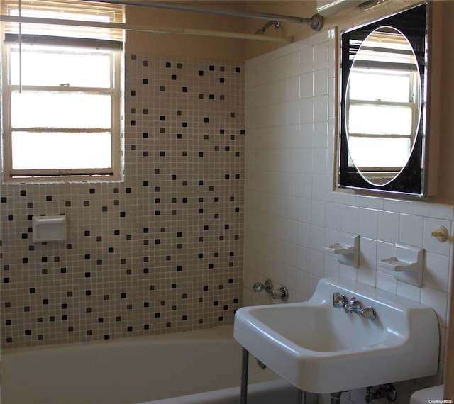 bathroom with backsplash, tiled shower / bath combo, and sink