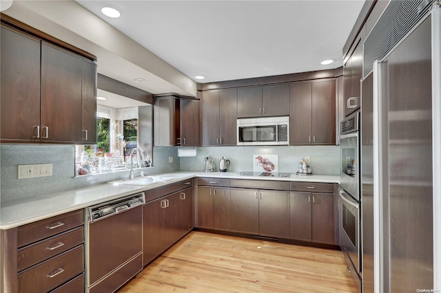 kitchen with sink, light hardwood / wood-style floors, dark brown cabinets, and appliances with stainless steel finishes