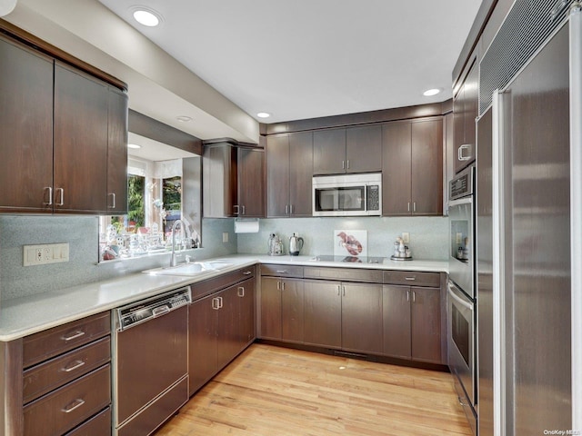 kitchen with dark brown cabinetry, sink, stainless steel appliances, and light wood-type flooring