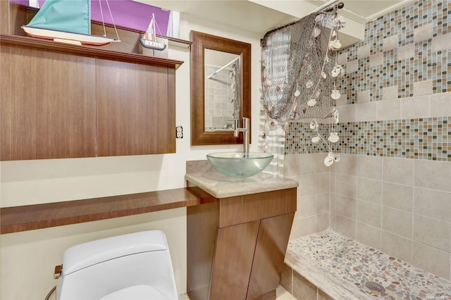 bathroom featuring vanity, toilet, and backsplash