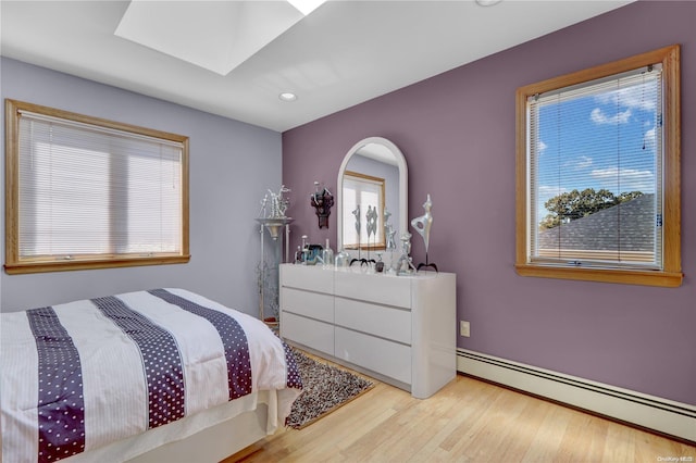 bedroom with a baseboard radiator and light hardwood / wood-style flooring