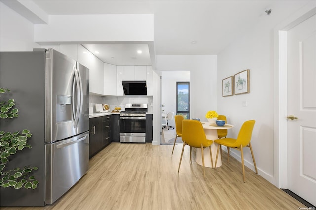 kitchen featuring backsplash, white cabinets, stainless steel appliances, and light hardwood / wood-style floors