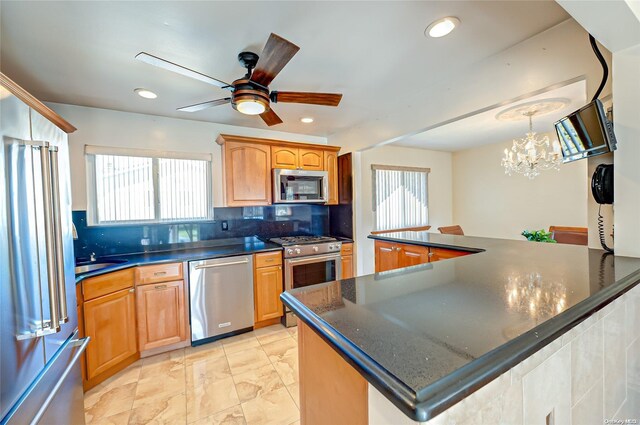 kitchen with a center island, tasteful backsplash, pendant lighting, ceiling fan with notable chandelier, and high end appliances