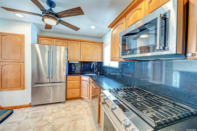 kitchen with ceiling fan, sink, premium appliances, tasteful backsplash, and dark stone countertops