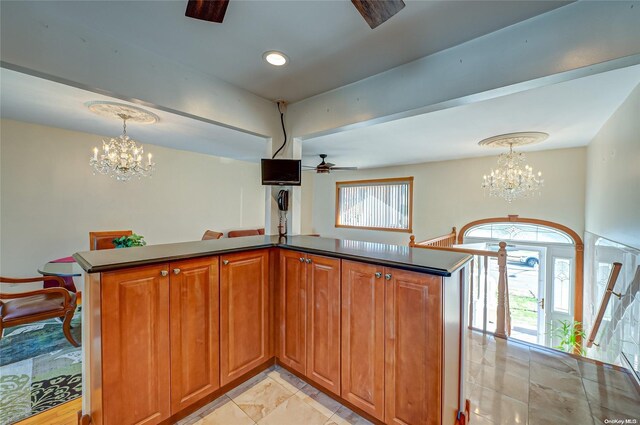 kitchen featuring plenty of natural light, kitchen peninsula, ceiling fan with notable chandelier, and decorative light fixtures