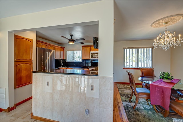 kitchen with decorative light fixtures, a healthy amount of sunlight, stainless steel appliances, and ceiling fan with notable chandelier