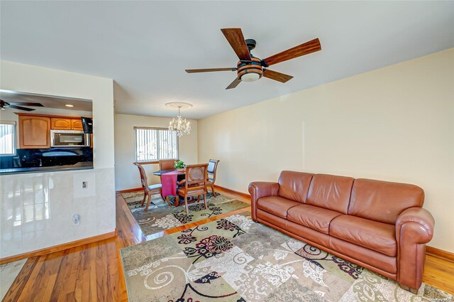 living room featuring ceiling fan with notable chandelier and light hardwood / wood-style floors