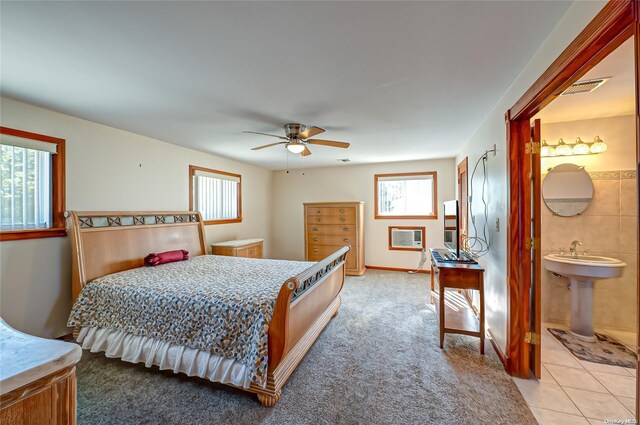 bedroom with ceiling fan, light colored carpet, and connected bathroom