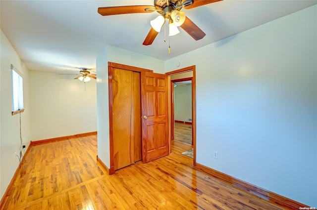 unfurnished bedroom with ceiling fan, light wood-type flooring, and a closet