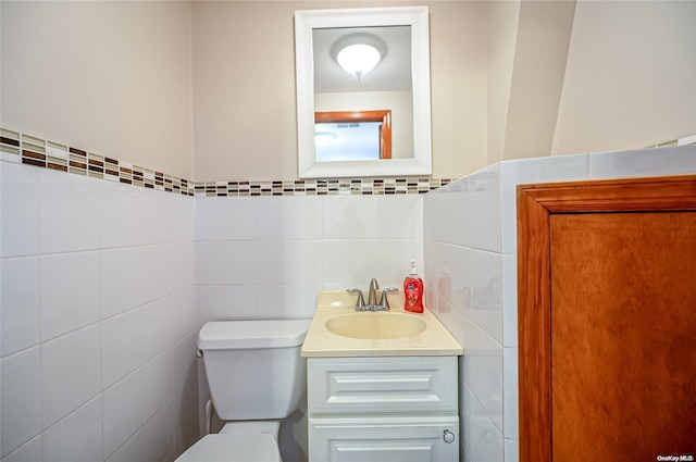 bathroom featuring vanity, toilet, and tile walls