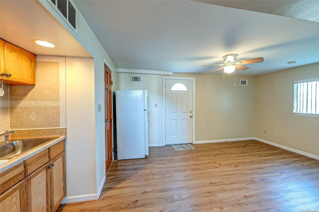 kitchen featuring ceiling fan, white refrigerator, light wood-type flooring, and sink