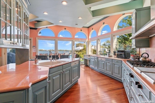 kitchen with stainless steel gas stovetop, wall chimney exhaust hood, light wood-type flooring, and a wealth of natural light