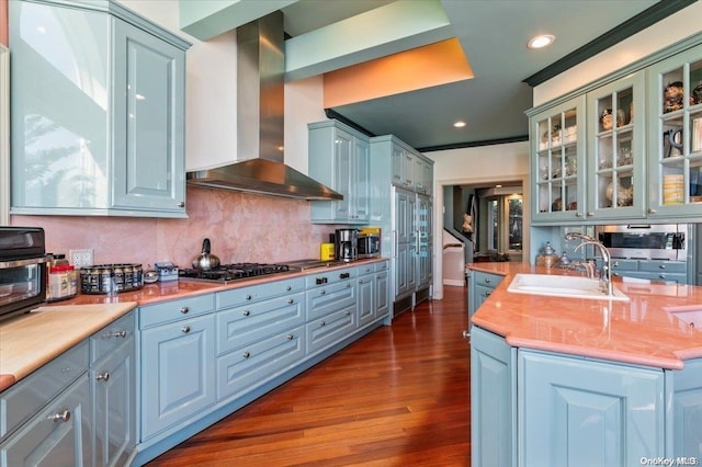 kitchen with dark hardwood / wood-style flooring, sink, wall chimney range hood, stainless steel gas stovetop, and butcher block counters