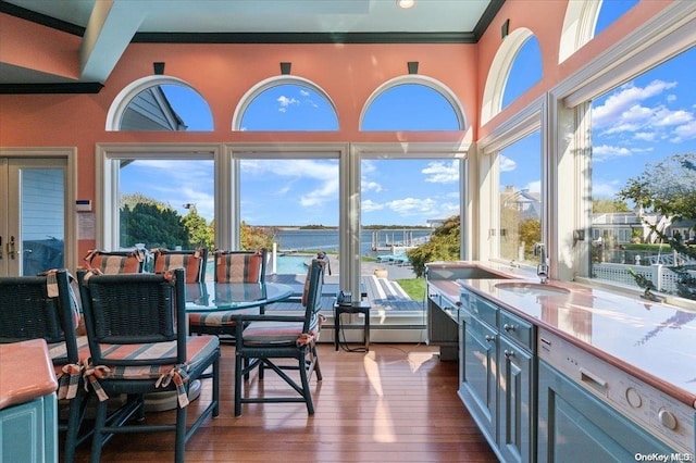 sunroom / solarium with a healthy amount of sunlight, a water view, sink, and a baseboard heating unit