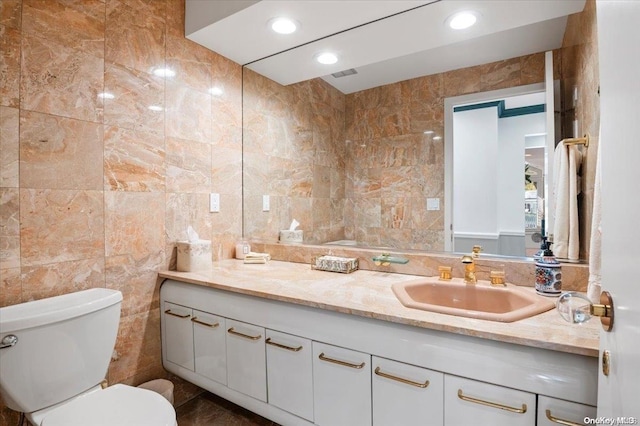 bathroom with vanity, toilet, and tile walls