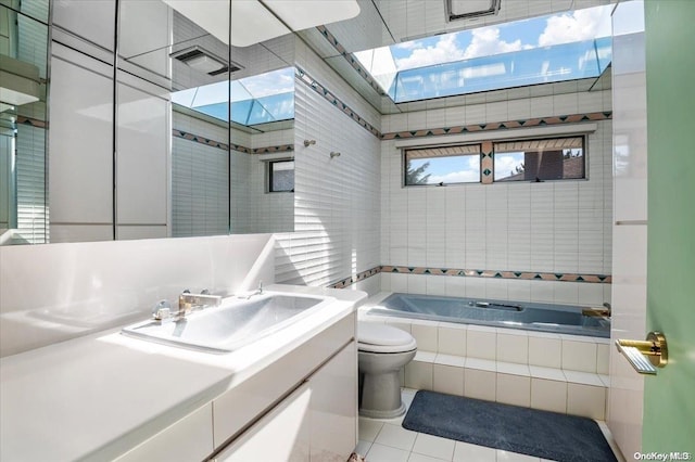 bathroom featuring toilet, vanity, a relaxing tiled tub, and tile patterned floors