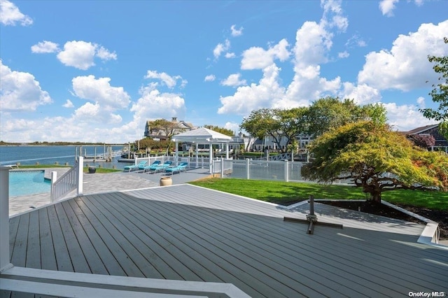 deck with a lawn, a water view, and a boat dock