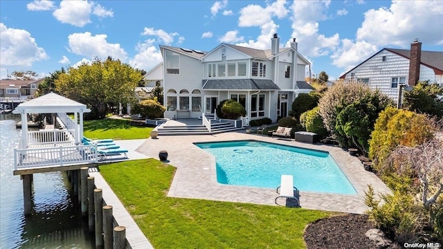 back of house featuring a pool side deck with water view, a lawn, a patio area, and a gazebo