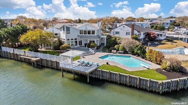 back of property with a water view, a fenced in pool, and a patio