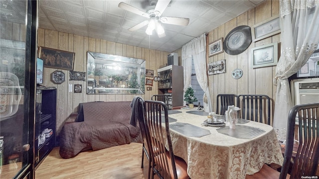 dining space featuring wooden walls, ceiling fan, and light wood-type flooring