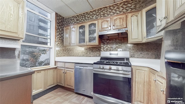 kitchen with a paneled ceiling, backsplash, stainless steel appliances, light brown cabinets, and range hood