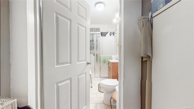 bathroom with tile patterned flooring, vanity, a shower with shower door, and toilet