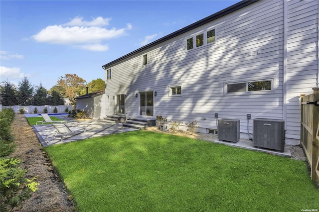 rear view of property with a lawn, a patio area, and central air condition unit