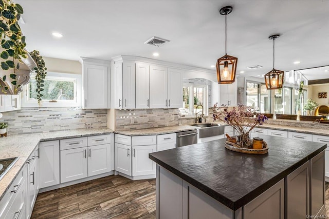 kitchen featuring dishwasher, a kitchen island, pendant lighting, dark stone counters, and white cabinets