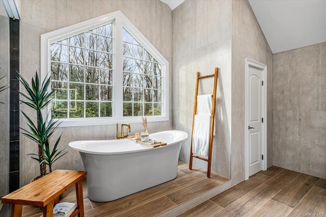 bathroom with lofted ceiling and a tub to relax in