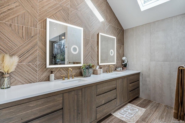 bathroom with vanity, lofted ceiling with skylight, and tile walls