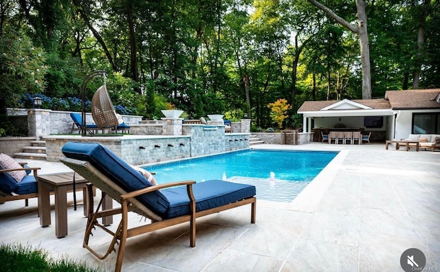 view of pool featuring an outbuilding, pool water feature, an outdoor bar, and a patio area