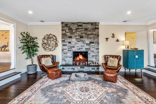 living area with a stone fireplace, wood-type flooring, and ornamental molding